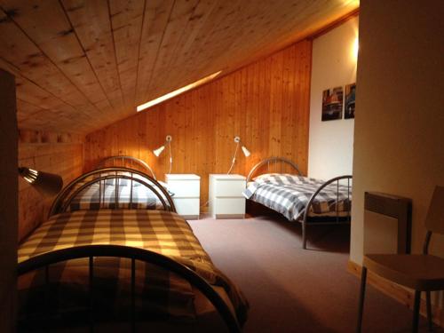 a room with two beds in a room with wooden walls at Between lake en ski resort in Thollon