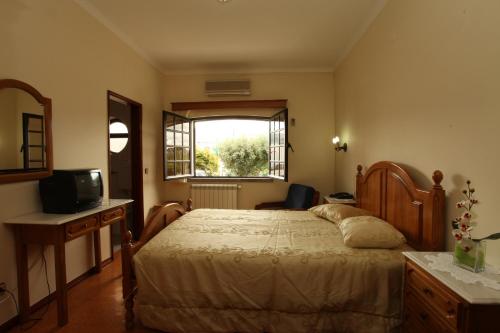 a bedroom with a large bed and a window at Residencial Sra. da Lomba in Pinhanços