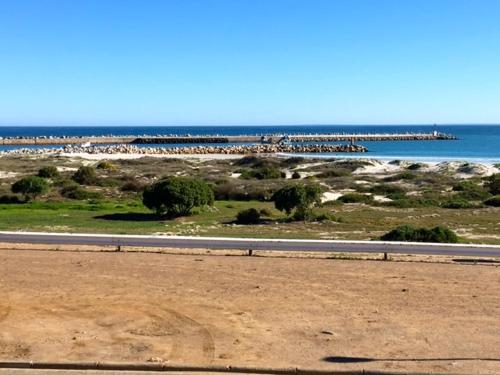 a road next to a beach with the ocean at Lazy Days Apartments - Lambert's Bay in Lambertʼs Bay