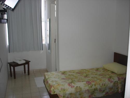 um pequeno quarto com uma cama e uma mesa em Delmus Hotel em Conselheiro Pena