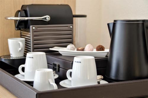 a tray with cups and plates and a coffee maker at Hotel Merkur - Superior in Baden-Baden
