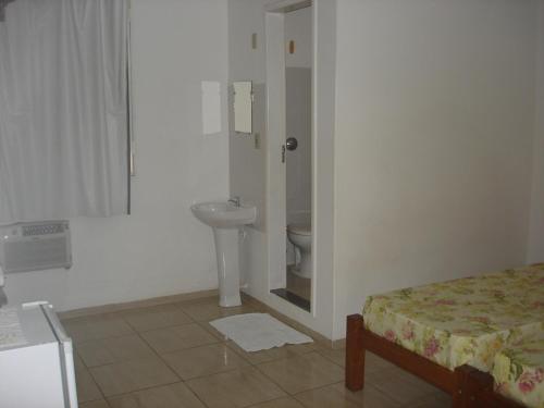 Un baño con lavabo e inodoro en una habitación. en Delmus Hotel, en Conselheiro Pena