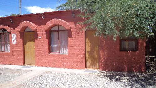 a red brick building with two doors and a tree at Hostal Las Kañas in San Pedro de Atacama
