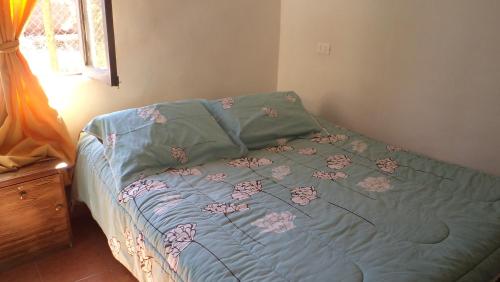 a bed with a blue comforter with flowers on it at Hostal Las Kañas in San Pedro de Atacama