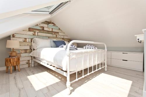 a bedroom with a white bed and a wooden wall at Coastguard Cottage in Bournemouth
