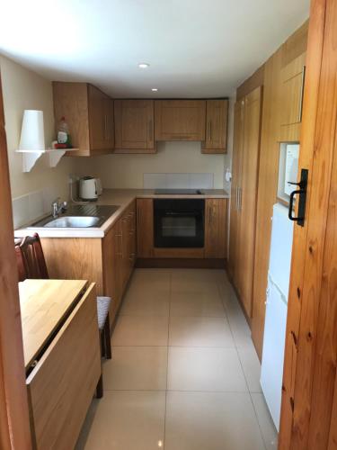 a kitchen with wooden cabinets and a white refrigerator at High Road Cottage in Achill