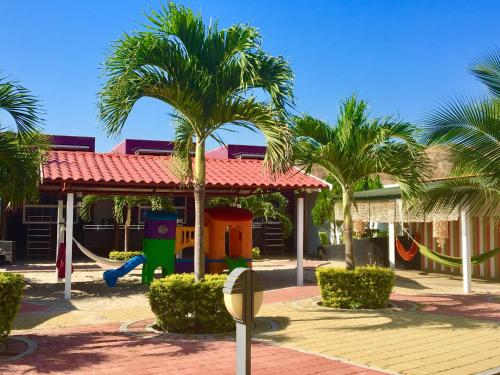 a playground in front of a house with palm trees at Hotel Casa Playa Zorritos in Zorritos