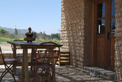 een tafel en stoelen op een patio met een deur bij Finca Huayrapuca in Famatina