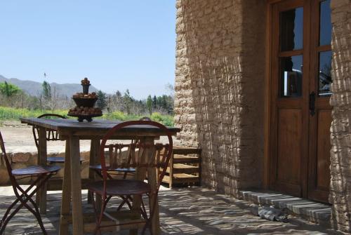 una mesa y sillas en un patio con puerta en Finca Huayrapuca, en Famatina
