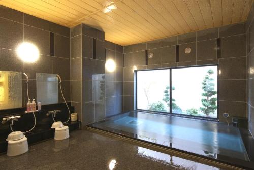 bagno con vasca e ampia finestra di Hotel Route-Inn Mitsukaido Ekimae a Joso