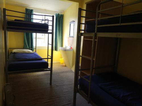 a room with two bunk beds and a bathroom at Napier Art House Backpackers in Napier