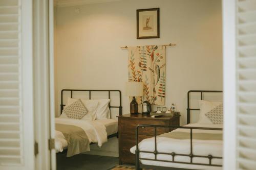 a bedroom with two beds and a table with a lamp at Brown Feather Hotel in Seminyak