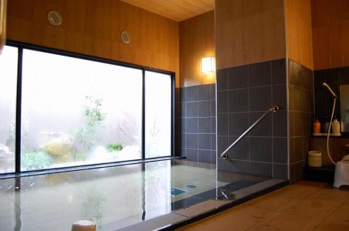 a bathroom with a shower and a tub with a window at Hotel Route Inn Toyota Motomachi in Toyota