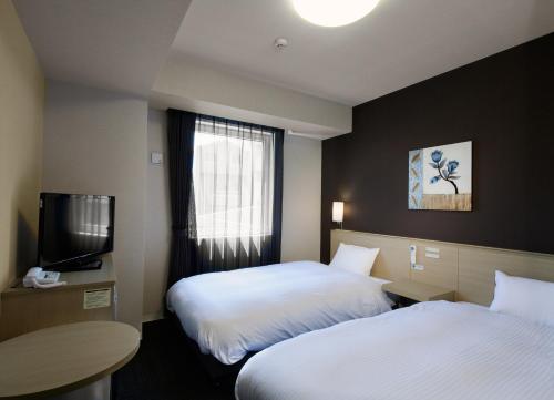 a hotel room with two beds and a television at Hotel Route-Inn Kamaishi in Kamaishi
