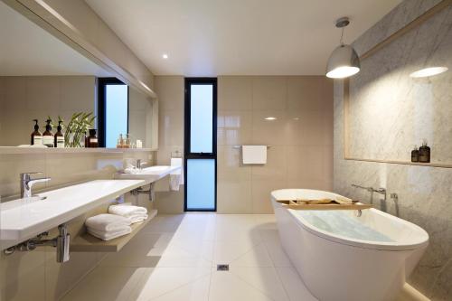 La salle de bains blanche est pourvue de 2 lavabos et d'une baignoire. dans l'établissement Flinders Hotel, à Flinders