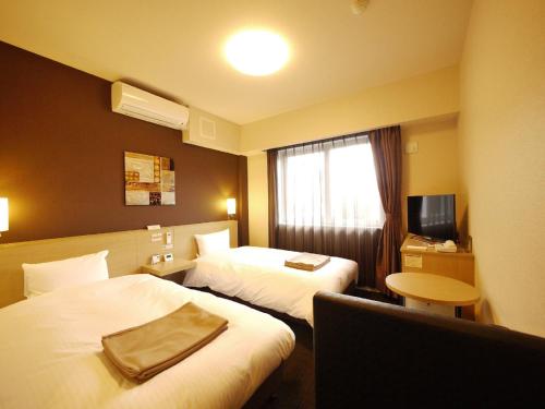 una camera d'albergo con due letti e una televisione di Hotel Route Inn Tagajo-Eki Higashi a Tagajo
