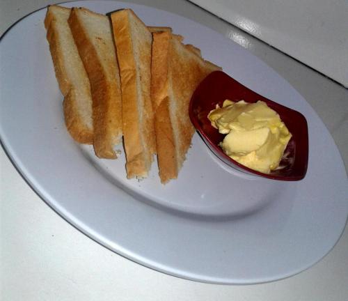 a white plate with a sandwich and a bowl of butter at Gubug Balian Beach Bungalow in Selemadeg