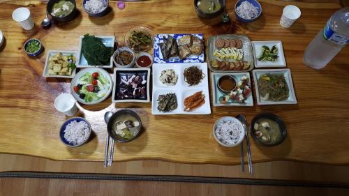 a wooden table topped with different types of food at Bangdigareum B&B in Seogwipo