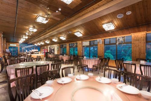 uma sala de jantar com mesas, cadeiras e janelas em Ming Chi Shan Zhuang em Datong