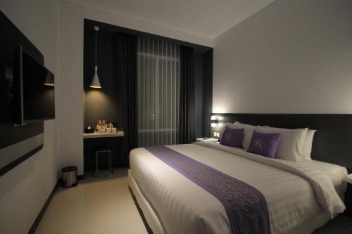 a bedroom with a large bed with purple pillows at Forriz Hotel Yogyakarta in Yogyakarta