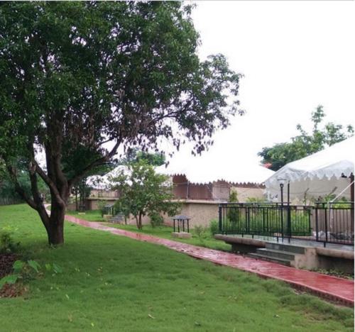a park with a tree and a bench in the grass at Sterling Kanha in Kānha