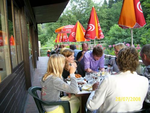 Chalet du Montal في Dun-les-Places: مجموعة من الناس يجلسون على طاولة يأكلون الطعام
