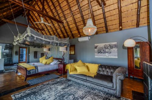 ein Schlafzimmer mit einem Bett und einem Sofa in der Unterkunft Nkorho Bush Lodge in Sabi Sand Game Reserve