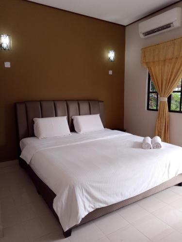 a bedroom with a large bed with two towels on it at Nas Villaria Langkawi in Pantai Cenang