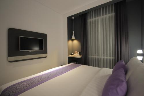 a hotel room with a bed and a tv at Forriz Hotel Yogyakarta in Yogyakarta