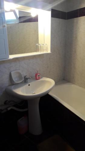 a bathroom with a white sink and a bath tub at Aris Rooms in Anogeia