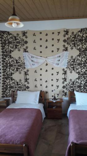 a bedroom with two beds and a wallpaper with bats at Aris Rooms in Anogia