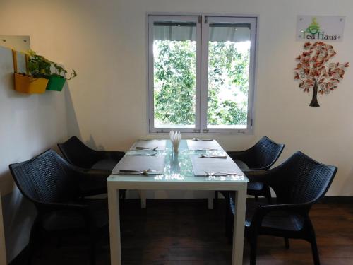 een tafel in een kamer met stoelen en een raam bij Moselberg Riverside Cottages in Munnar