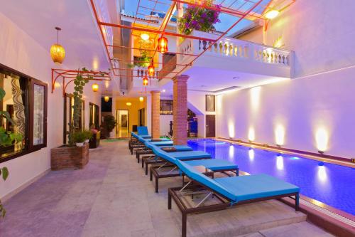 a pool with a row of blue chairs in a building at Pham Gia Boutique Villa in Hoi An