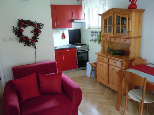 a kitchen with red cabinets and a red chair at Apartma Dobrna in Dobrna