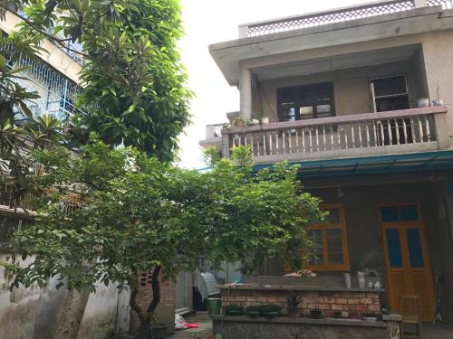ein Haus mit einem Balkon und einem Baum davor in der Unterkunft No. 6 Cuobian Hostel in Shantou