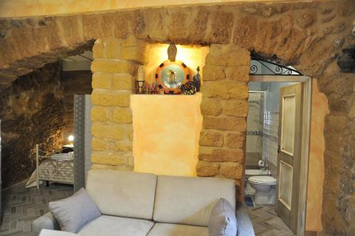 sala de estar con sofá y pared de piedra en Grotta Dei Greci en Agrigento