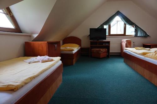 a attic room with two beds and a tv at Penzion Martin in Janske Lazne