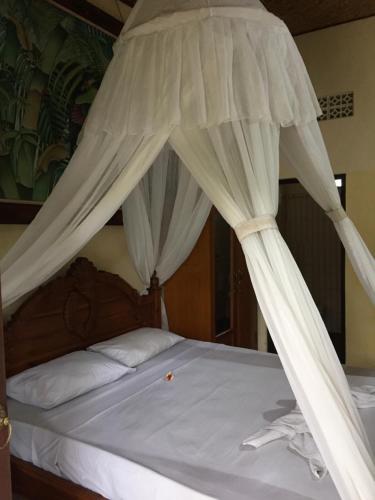 Una cama con dosel y cortinas blancas. en Batan Duren House, en Ubud