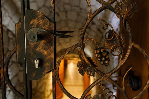 a metal gate with grapes on it with a doorway at Tokaj Zlatá Putňa - Restaurant & Pension in Viničky