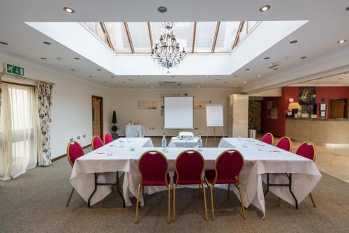 a conference room with a long table and red chairs at Golden Lion Hotel in Rugby