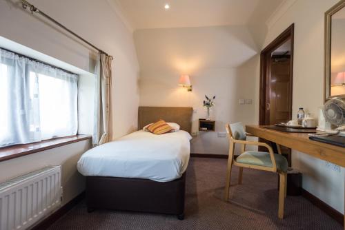 
a bedroom with a bed and a desk at Golden Lion Hotel in Rugby
