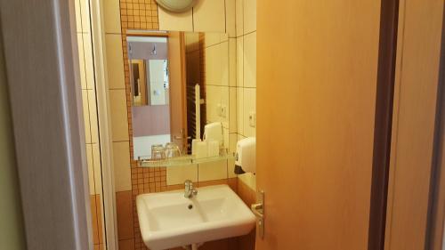 ein Bad mit einem Waschbecken und einem Spiegel in der Unterkunft Lehár panzió in Komárno