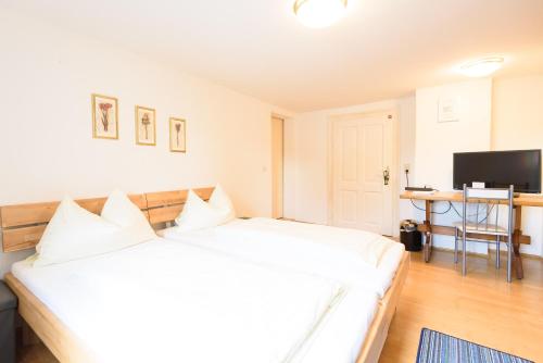 a bedroom with a large white bed and a desk at Gasthof Wastlwirt in Salzburg