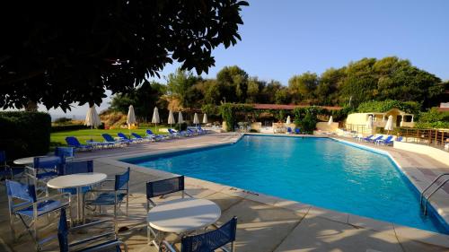 a swimming pool with blue chairs and tables and chairs at Karavados Beach Hotel in Karavadhos