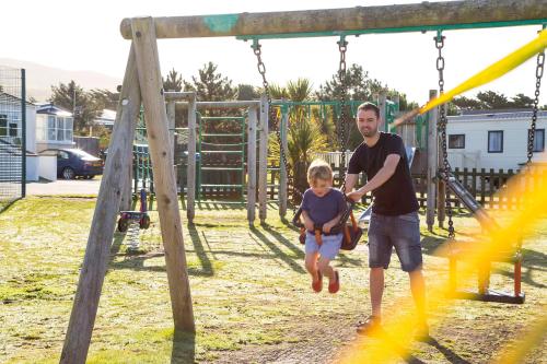 a man and a little girl on a swing at Barmouth Bay Holiday Park in Barmouth