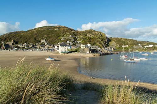 a beach with boats in the water and a town at Barmouth Bay Holiday Park in Barmouth