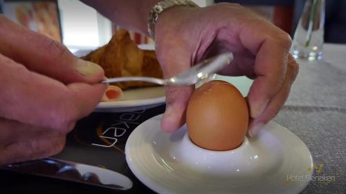 a person eating an egg on a plate at Best Western Hotel Slenaken in Slenaken
