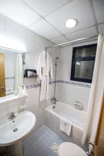a bathroom with a sink and a tub and a toilet at Welcome Hotel Apartments 1 in Dubai