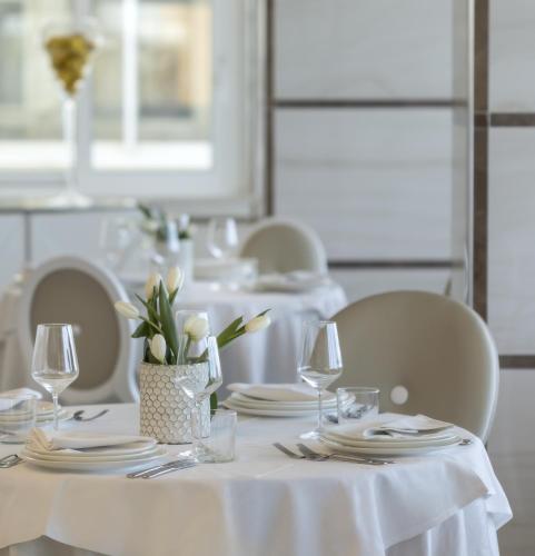 a white table with plates and glasses and flowers on it at Hotel Tiffany's in Riccione