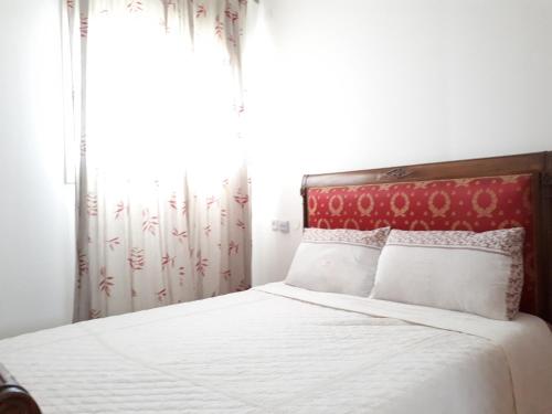um quarto com uma cama com uma cabeceira vermelha e uma janela em Shoam street apartment sea view Ashdod em Ashdod